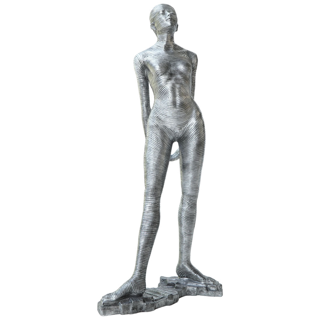 A metallic silver sculpture of a standing nude female figure with a textured, ribbed surface, set against a plain white background.