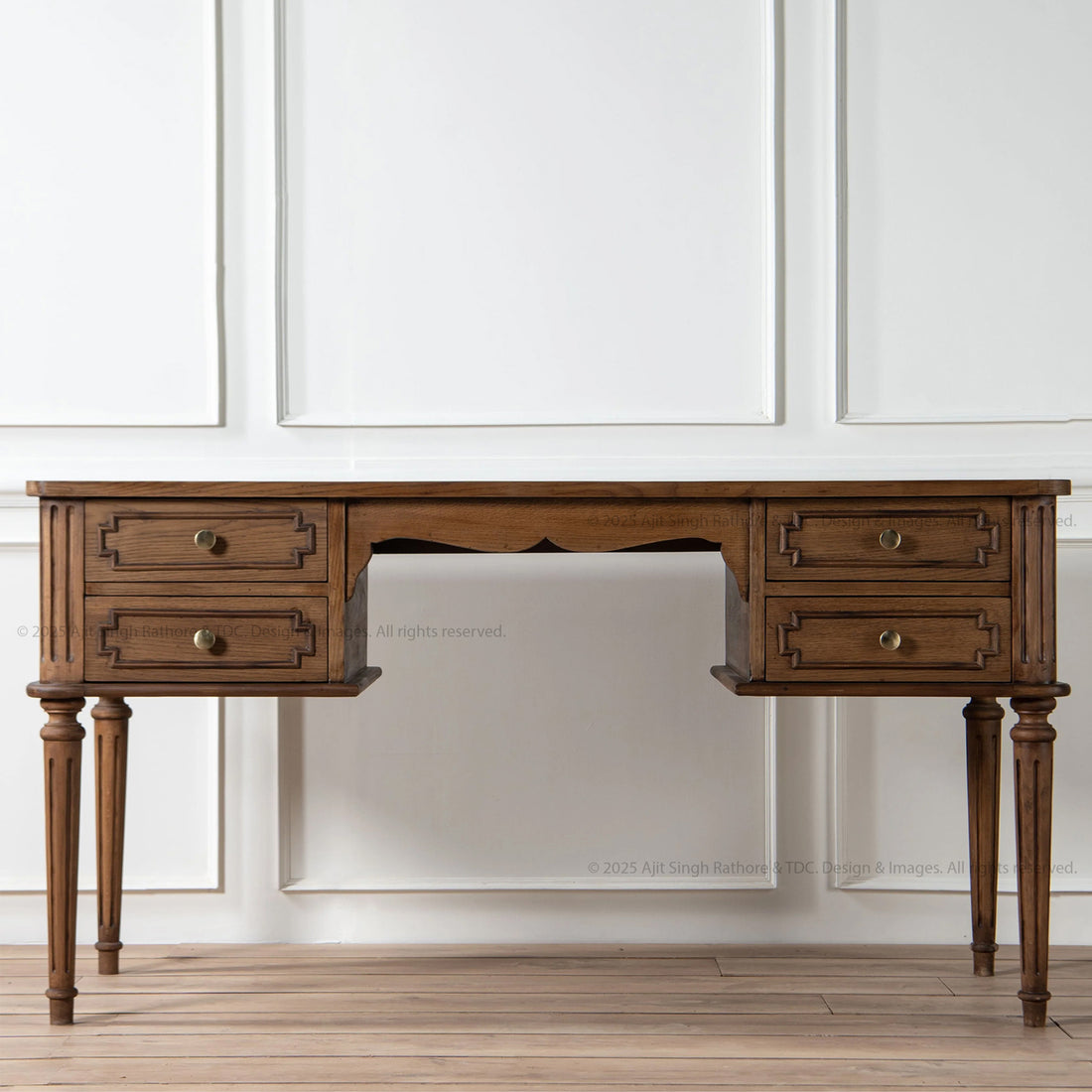 A solid wood writing desk with four drawers, featuring intricate carvings and fluted legs, set against a white background.
